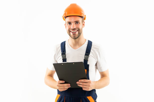 istock happy man in hardhat holding clipboard isolated on white background, builder 1412254509