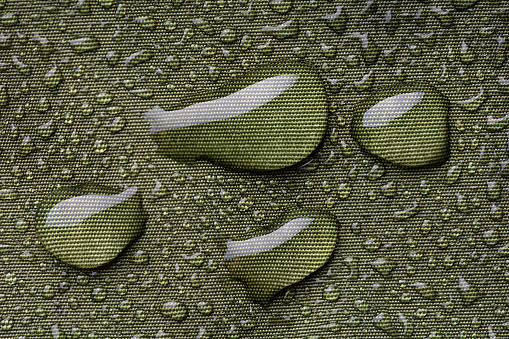 Raindrops beading on waterproof green nylon jacket - extreme close up from above
