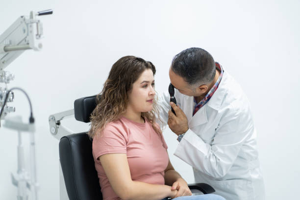 istock Ophthalmologist holding device to look at woman's eye 1412258256