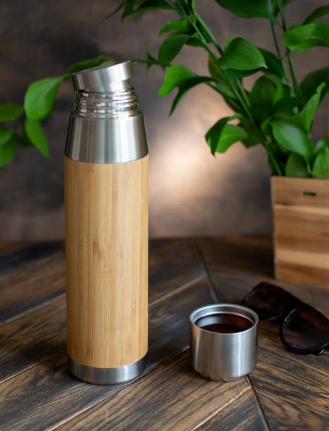 istock Thermos  bottle bamboo with open cup on wooden table 1412258353