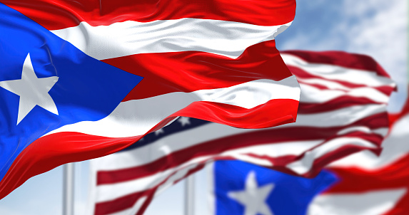 Banderas de Puerto Rico ondeando al viento con la bandera de Estados Unidos en un día despejado photo