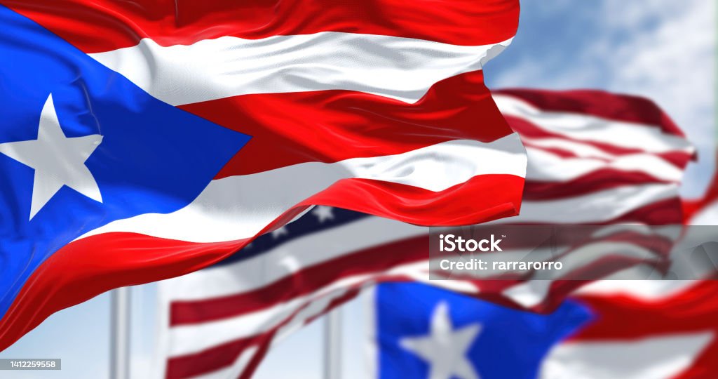 Flags of Puerto Rico waving in the wind with the United States flag on a clear day Flags of Puerto Rico waving in the wind with the United States flag on a clear day. Puerto Rico is a Caribbean island and unincorporated territory of the United States Puerto Rico Stock Photo