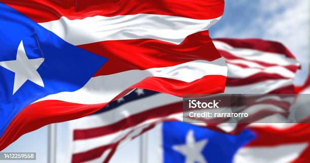 Flags Of Puerto Rico Waving In The Wind With The United States Flag On A Clear Day Stock Photo - Download Image Now