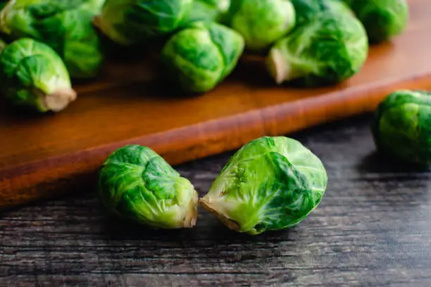 Closeup view of fresh Brussels sprouts scattered on a wood cutting board