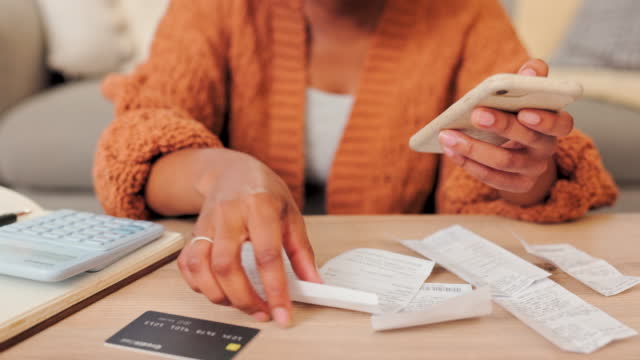Expenses, credit card bills, payment and tax calculations with receipts for a budget. Closeup of female adding up her salary, costs and spending on a phone. Lady planning bank account balance