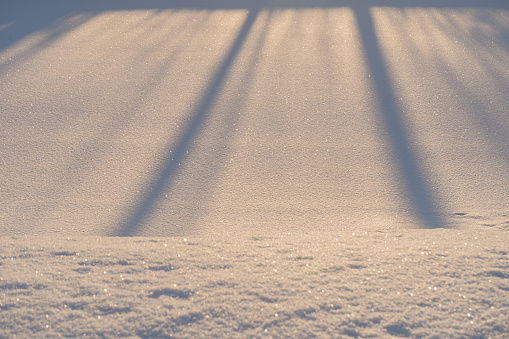 Shadows  on snowy surface by the sunlight. Abstract winter background.