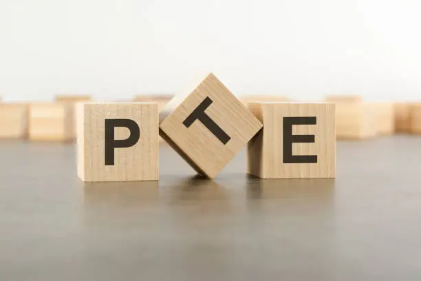 wooden cube with the letter from the PTE word. wooden cubes standing on gray background. PTE - short for Pearson Tests of English.