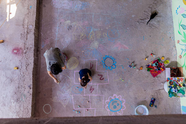 Mother and daughter drawing with chalk on the concrete