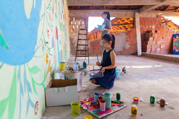istock Mother and daughter, using her creative skills to draw the mural with a theme 