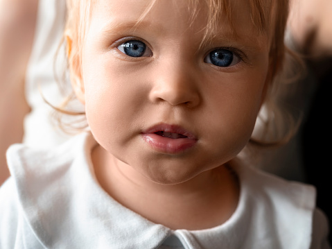 Close-up portrait of a blue eyed baby. Little baby looking at camera.