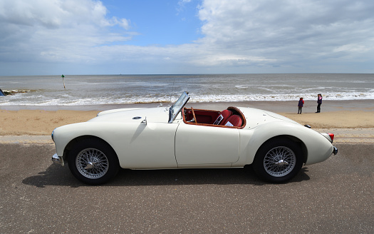 Felixstowe, Suffolk, England -  May 05, 2019:  Classic  White  MGA motor car parkrd on  seafront  promenade beach and sea in background.