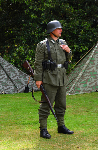 Silsoe, Bedfordshire, England - August 14, 2021: Infantryman from reenactment group in WW2  German uniform with  Mauser Rifle.