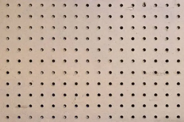 Closeup of an empty section of a pegboard wall in a garage/workshop.