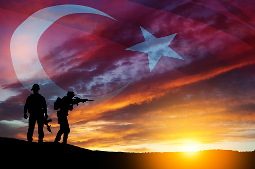 Silhouettes of soldiers on a background of Turkey flag and the sunset or the sunrise. Concept of crisis of war and conflicts between nations. Greeting card for Turkish Armed Forces Day, Victory Day.
