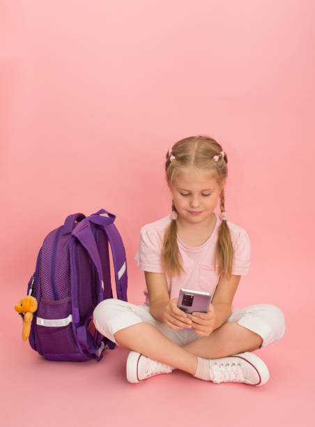 istock Little girl with school backpack and using  smart phone. Back to school concept. 1412279435