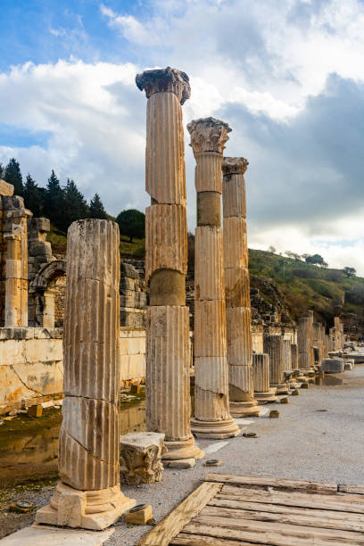 Remaining elements of State Agora columns with Corinthian capitals in ancient Greek city of Ephesus with Odeon ruins in background, Selcuk, Turkey