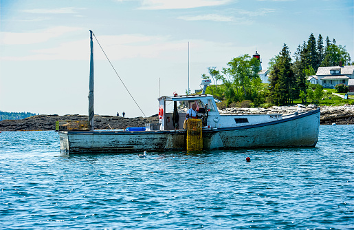 Local lobster fisherman checking their traps off the coast of Boothbay Harbor, Maine.  Boothbay Harbor is a popular summer tourist attraction for boaters, shoppers and vacationers.