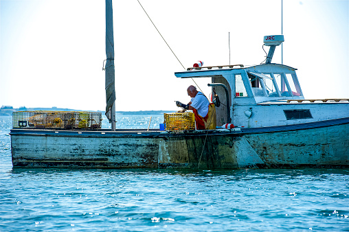 Local lobster fisherman checking their traps off the coast of Boothbay Harbor, Maine.  Boothbay Harbor is a popular summer tourist attraction for boaters, shoppers and vacationers.