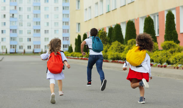 istock Cute white and black students are running back to school. 1412287111