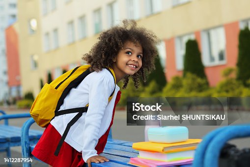 istock Cute Black schoolgirl eating lunch outdoors next the school. Healthy school breakfast for child. 1412287954