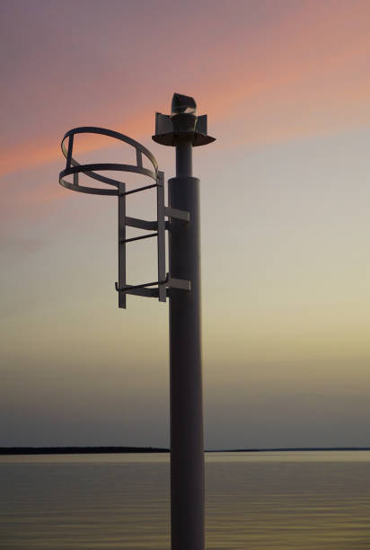 A small metal lighthouse in the village harbor during colorful sunset