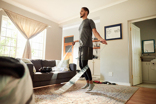 Fit young man in sportswear skipping with a rope in his living room during a home workout session