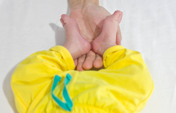 young family of mother of the father and kid. Mother and the father hold legs of the newborn child in the palms.