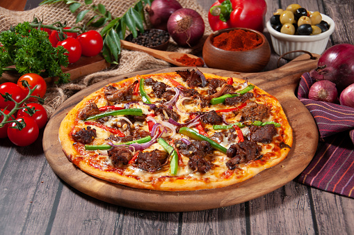 Beef Rendang Pizza with tomato, onion, chili powder, and black pepper isolated on wooden cutting board side view of fastfood on wooden table