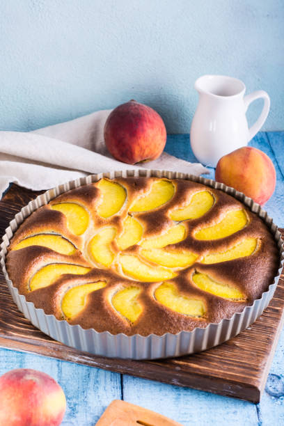 istock Ready fresh peach pie in a baking dish on the table. Homemade dessert. Vertical view 1412293256