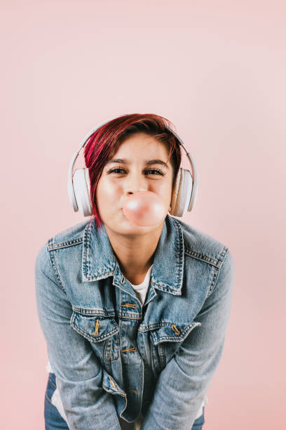 portret latynoskiej młodej kobiety z kolorową gumą do żucia włosów i słuchawkami słuchającą muzyki w meksyku ameryka łacińska - chewing gum audio zdjęcia i obrazy z banku zdjęć