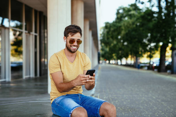 Man using smart phone, image taken in summertime, copy space on sides, easy to turn into vertical image