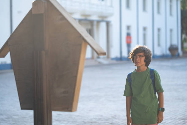 A cheerful young man standing outdoors, enthusiastically checking his mailbox at a suburban home.