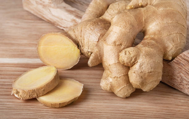 Fresh ginger root whole and slices on wood background.