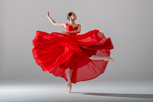 young graceful ballerina, dressed in pointe shoes and a weightless red skirt, demonstrates her dancing skills. The beauty of classical ballet.