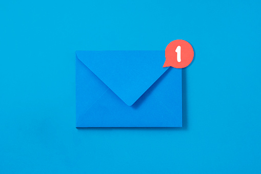 Blue envelope with message symbol attached on it on blue background