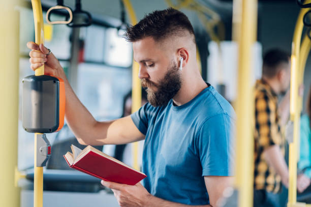 istock Man is riding in a bus and reading a book while holding for a bar 1412305454