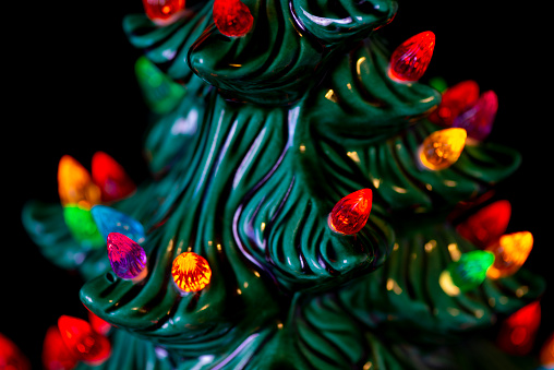 Green ceramic Christmas Tree with colored lights isolated on a black background.   The tree is decorated various colorful lights with a star on top.  The ceramic tree is covered with a glossy fired glaze.   Makes a good Christmas or religious holiday decorations.