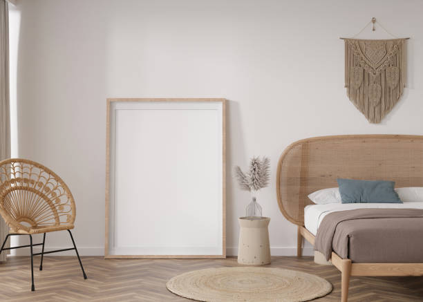 istock Empty vertical picture frame standing on parquet floor in modern bedroom. Mock up interior in boho style. Free space for picture or poster. Bed, macrame, rattan armchair, pampas grass. 3D rendering. 1412307819