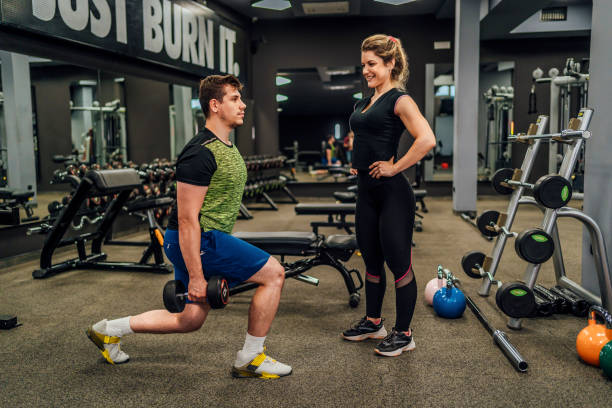 istock Man exercises with personal trainer in gym 1412308135