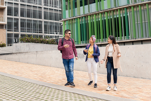 a Latin mid adult man talking to two women while walking on the street