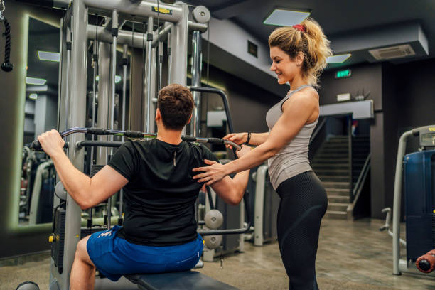 istock Man working out on Lat machine with assistance of instructor 1412308398