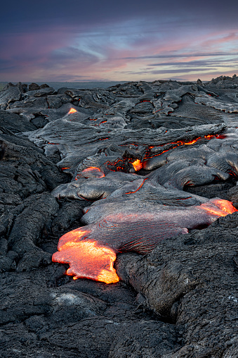 Erupting lava at dusk in Hawaii oozes up through the earth's crust to form new volcanic rock.