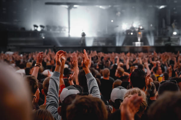 desempenho de um grupo popular. a multidão com as mãos levantadas contra a luz do palco. - popular music concert music event crowd - fotografias e filmes do acervo