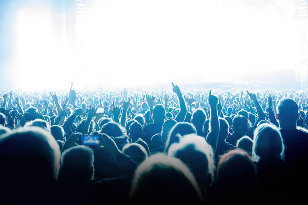 istock Performance of a popular group. The crowd with raised hands against the stage light. 1412313394