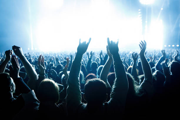 istock Performance of a popular group. The crowd with raised hands against the stage light. 1412313402