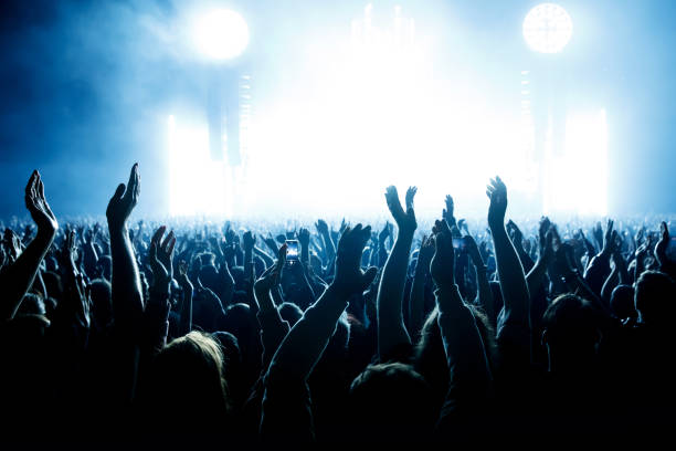 istock Performance of a popular group. The crowd with raised hands against the stage light. 1412313417