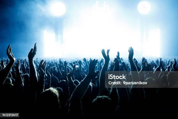 Performance Of A Popular Group The Crowd With Raised Hands Against The Stage Light Stock Photo - Download Image Now