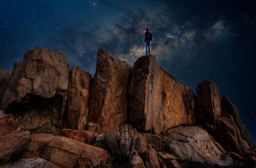 man standing on the rock outdoors staring the Milky Way, back view