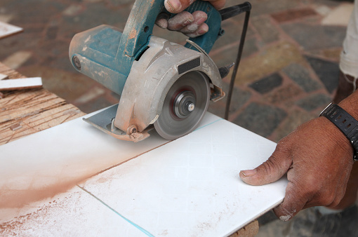 Man Cuts a Tile Using Appropriate Equipment