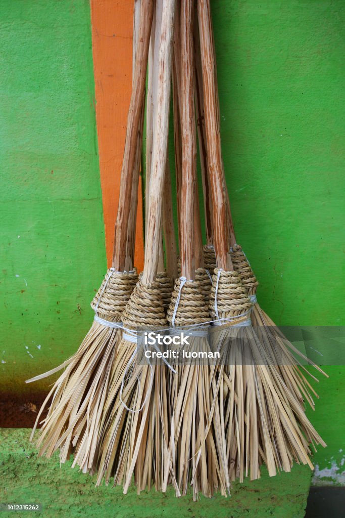 New brooms hanging Brooms made of straw. Displayed for sale in a market. Antique Stock Photo